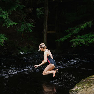 Woman jumping into river at Camp Glen Dye